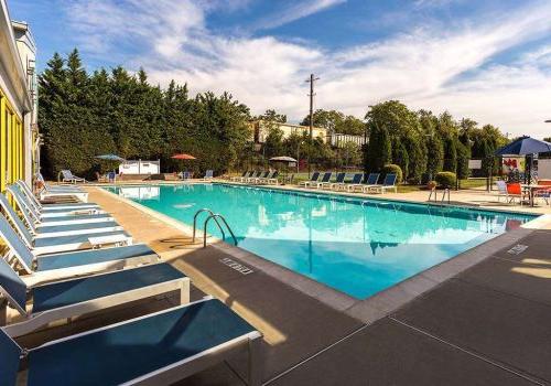 Outdoor pool with lounge chairs, tables, and umbrellas at 网关塔 at Packer Park apartments